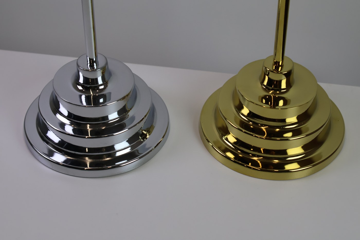 Chrome plated and gold plated metal desktop flagpole bases side by side